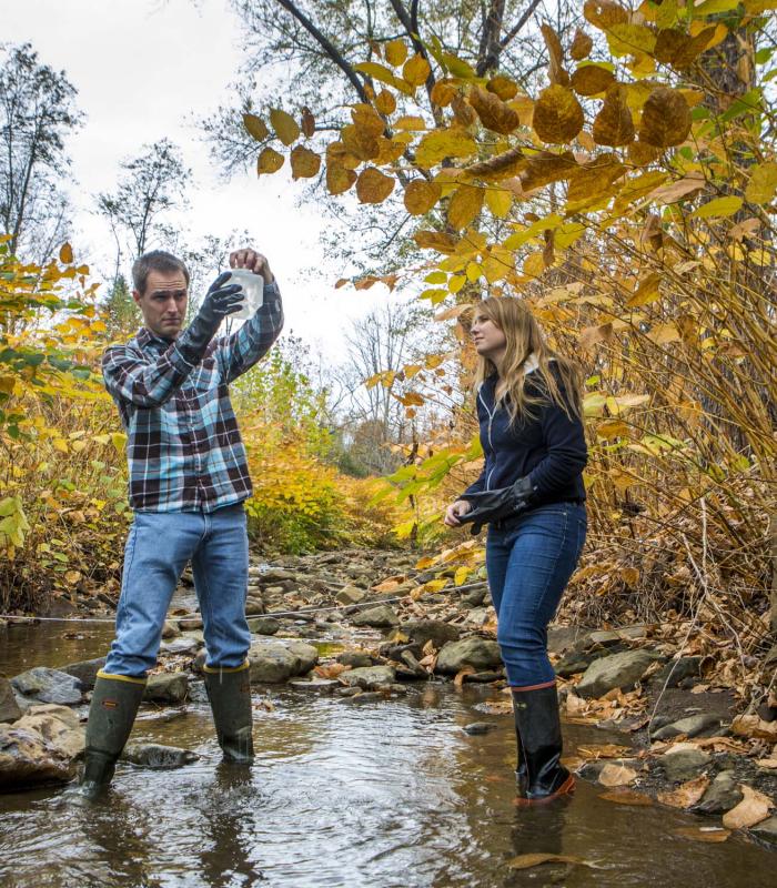 two people testing water in a stream